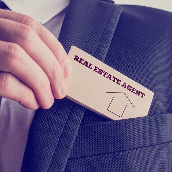 Real,Estate,Agent,In,Black,Suit,Putting,Small,Wooden,Piece